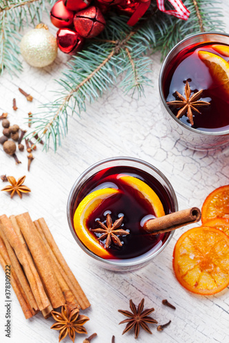 Mulled red wine with spices, orange slices on wooden new year and Christmas background. Top view.