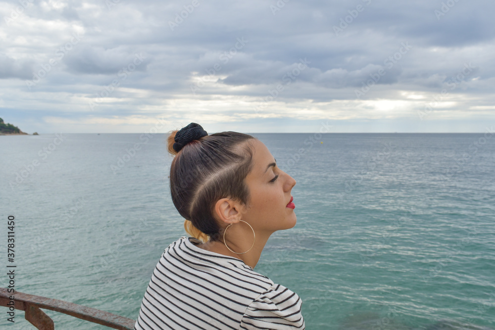 Young woman with red lipstick, photographed by the sea on an autumn day. Young woman with red lipstick, photographed by the sea on an autumn day.