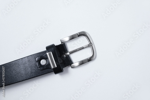 Metal buckle of male black leather belt on a white background close-up.