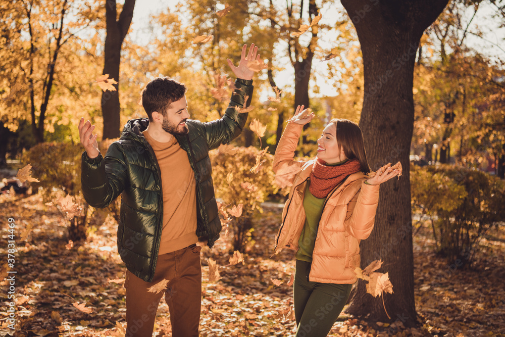 Photo of positive cheerful girl throw september leaves air in fall city forest park wear october coats