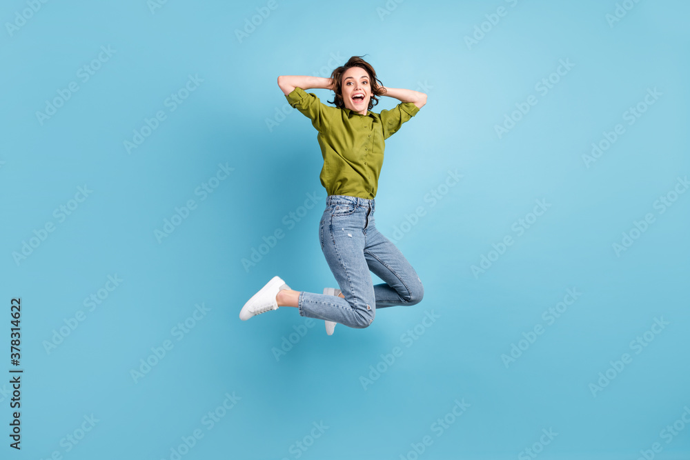 Photo portrait of excited woman jumping up holding head with hands isolated on pastel light blue colored background