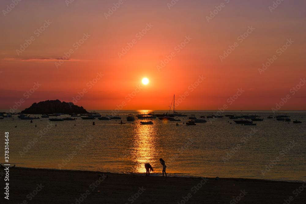 Silhouette of two friends enjoying on the beach during sunrise on the Costa Brava.