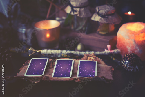 3 Tarot cards spread lying on a black table with magic items. Toned to cold colors in shadows.