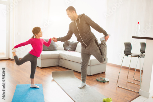 father and daughter are training at home. Workout in the apartment. Sports at home. They do exercises with yoga or Pilates.