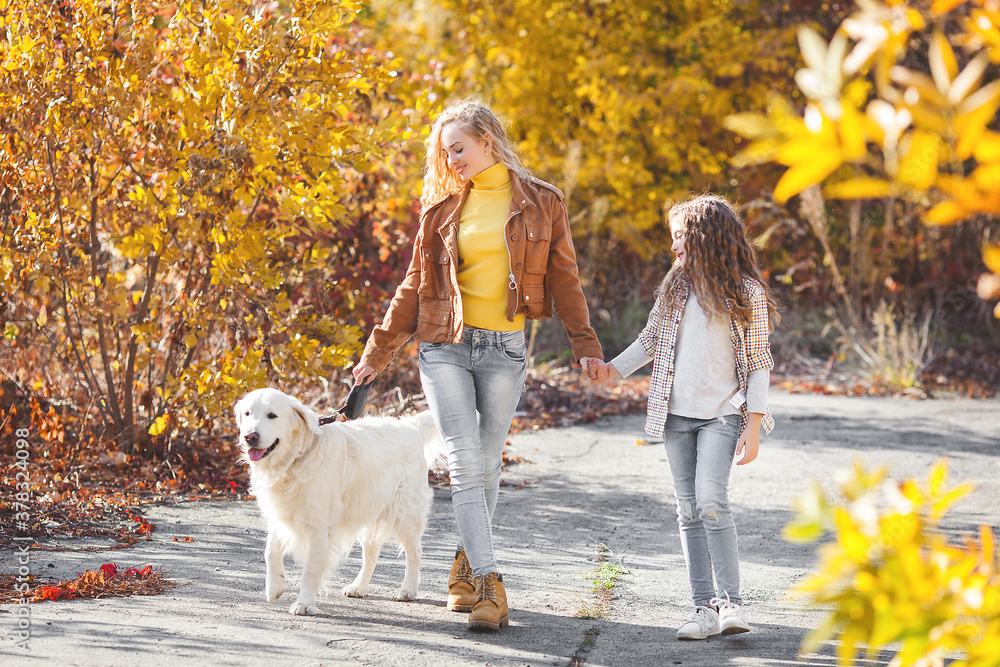 Two cute girls walking with their pet. Sisters and dog at autumn background