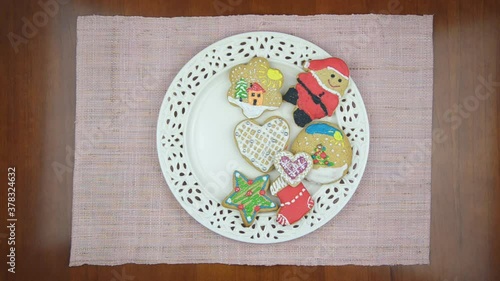 White porcelain plate full of ginger cookies on a wooden table and pink tablecloth. Every one second, one by one, cookies are disappearing. Last cake is a heart figure.