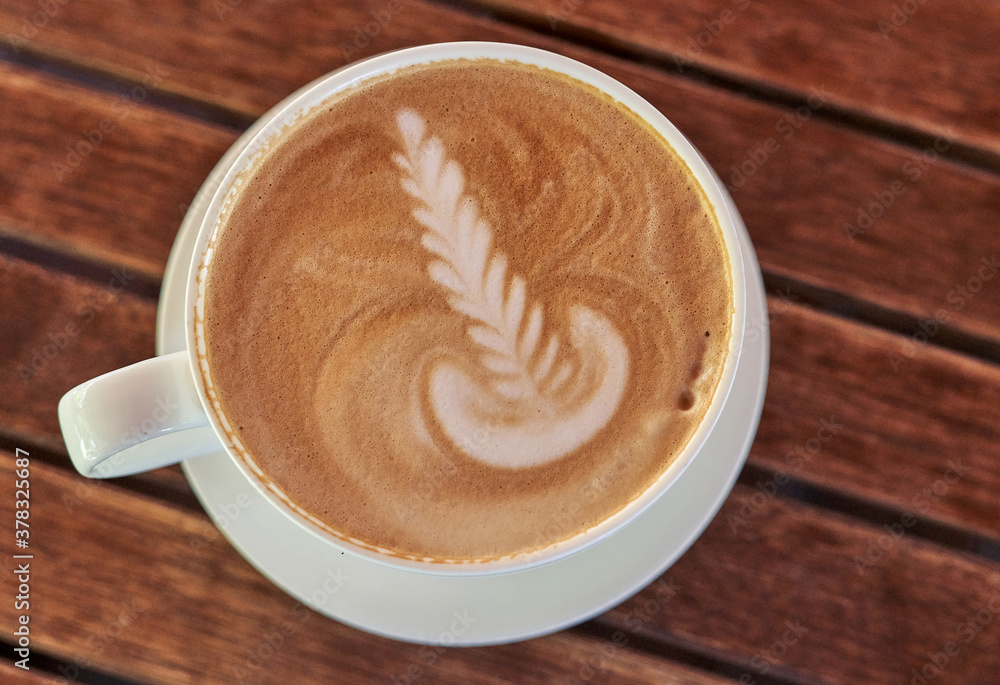 Drawing on the coffee foam. White saucer and cup with coffee, top view Drawing on the coffee foam. White saucer and cup with coffee, top view