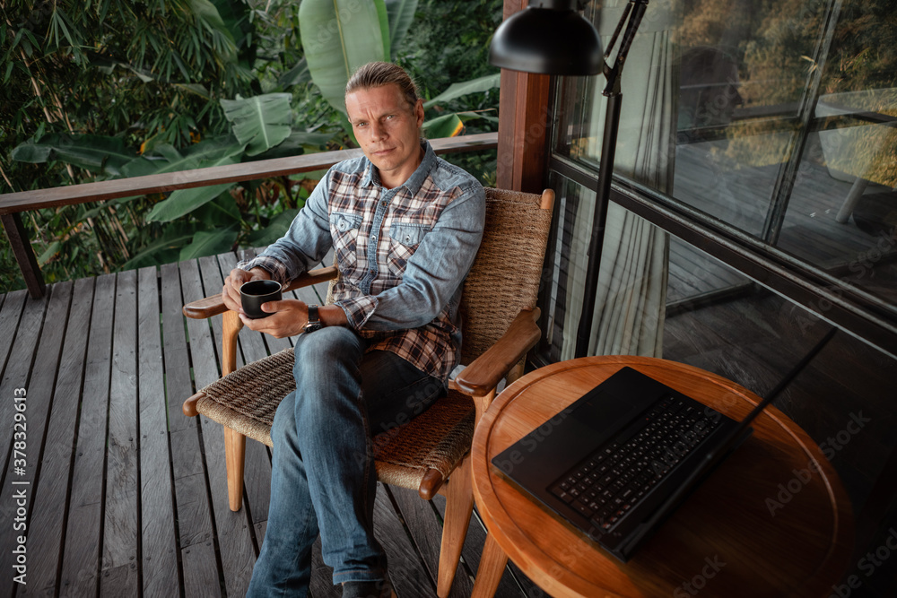 Entrepreneur man working with a laptop in a restaurant terrace or home balcony, drnk coffee Entrepreneur man working with a laptop in a restaurant terrace or home balcony, drnk coffee