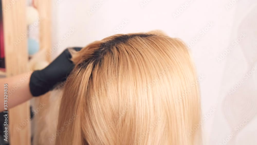 View from above. A woman distributes strands of beautiful blond hair to a client in a hairdressing salon. Coloring, haircut, hair styling in a beauty salon. View from above. A woman distributes strands of beautiful blond hair to a client in a hairdressing salon. Coloring, haircut, hair styling in a beauty salon.