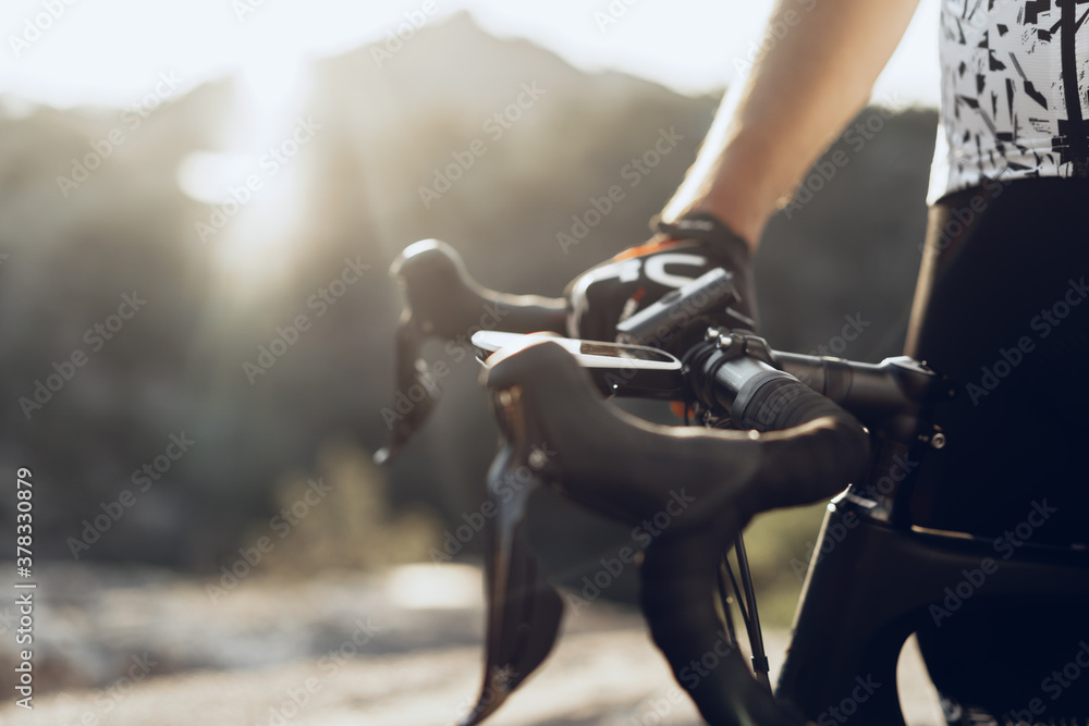 Obraz premium Hands of a professional cyclist in gloves on handle bar of a bicycle