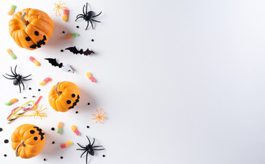 Halloween decorations made from pumpkin, paper bats and black spider on white background. Flat lay, top view with copy space for text.