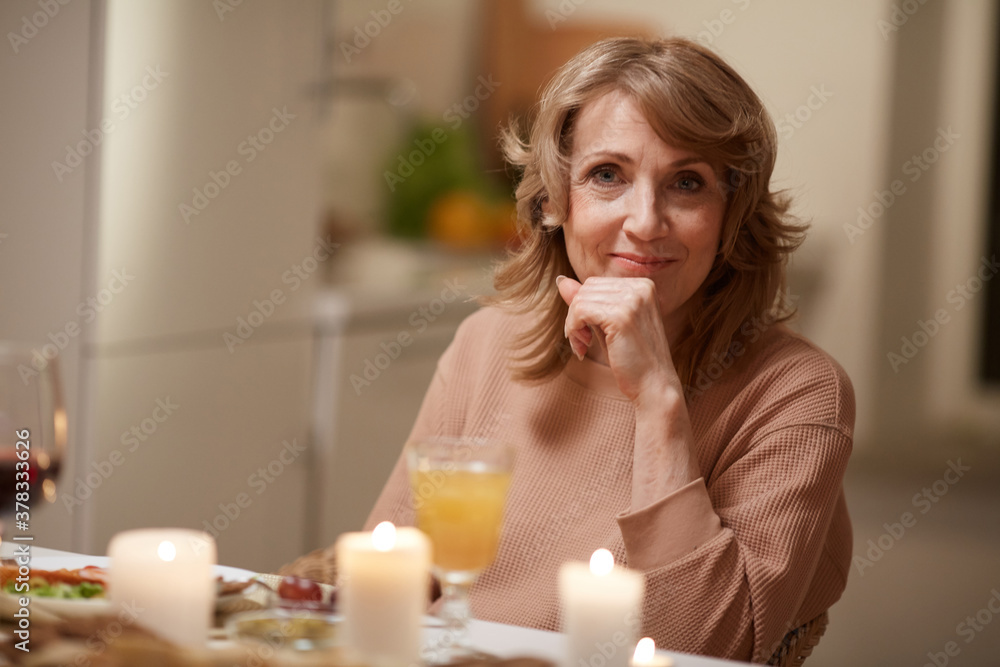 Portrait of mature woman looking at camera while sitting at dining table she has dinner Portrait of mature woman looking at camera while sitting at dining table she has dinner