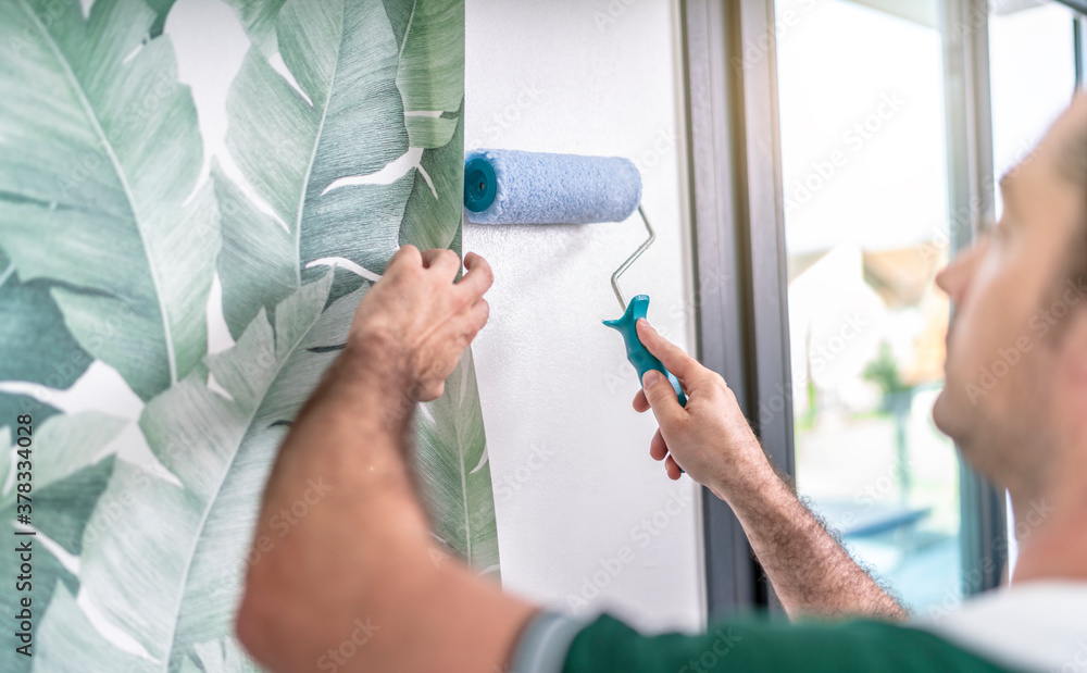 Handwerker streicht die Wand mit der Rolle mit Kleister ein Handwerker streicht die Wand mit der Rolle mit Kleister ein