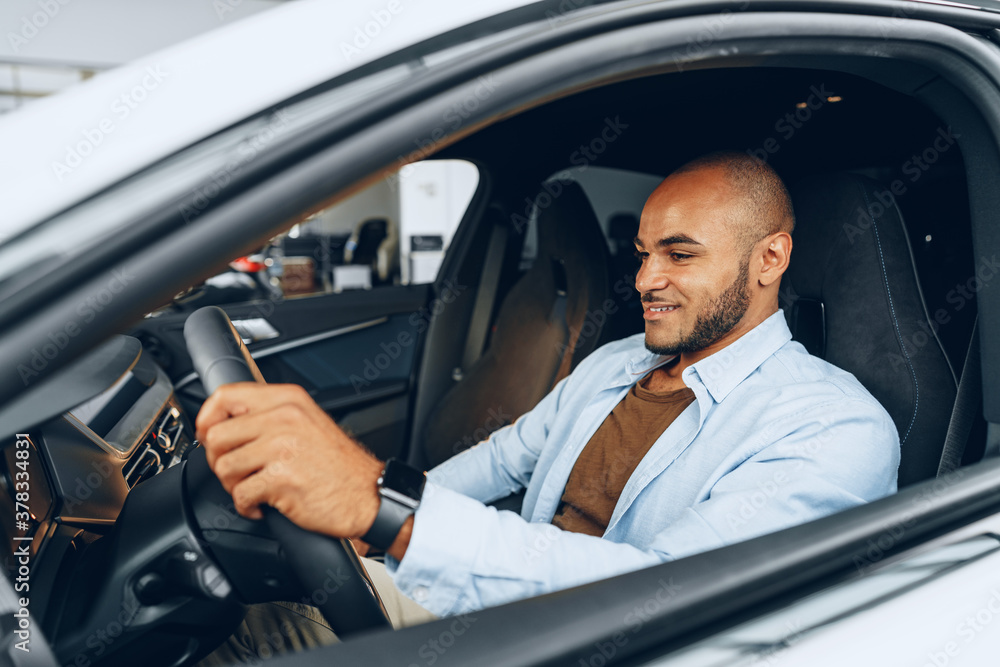 Portrait of a handsome happy African American man sitting in his newly bought car Portrait of a handsome happy African American man sitting in his newly bought car