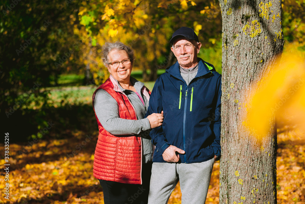 Happy senior couple in love in autumn park. Smiling mature man and old woman having fun outdoors