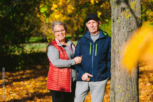 Obraz na płótnie Happy senior couple in love in autumn park. Smiling mature man and old woman having fun outdoors w salonie