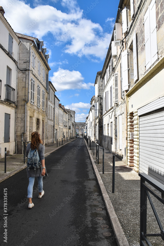 Young girl with backpack walking down an empty street
