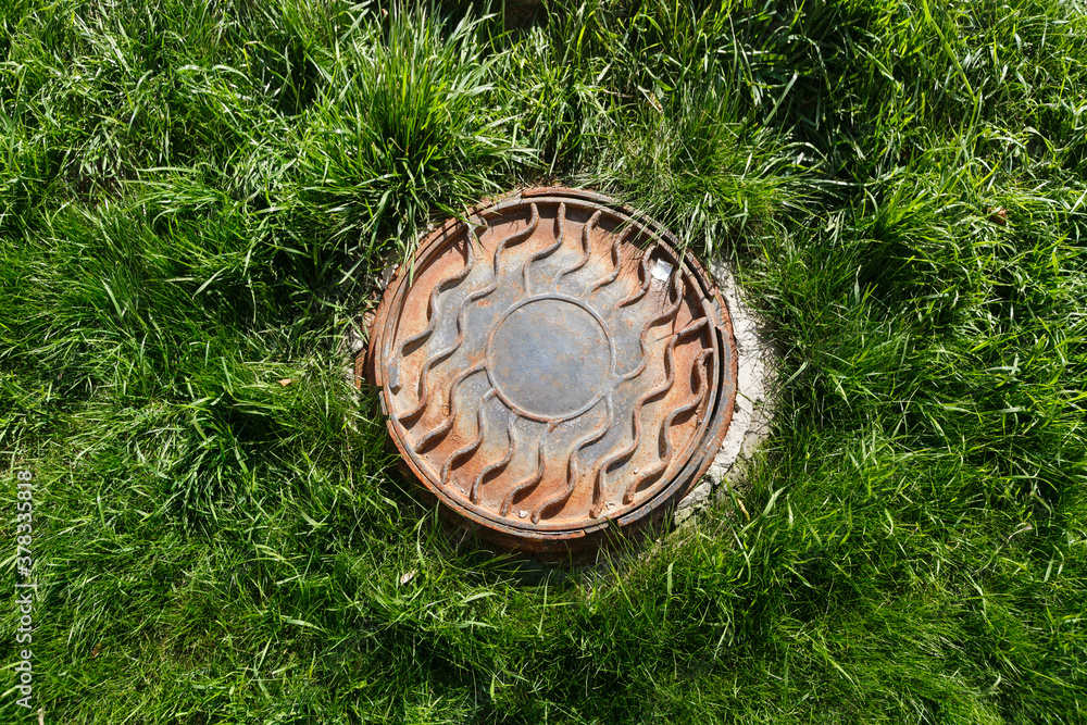 Fototapeta premium Metal manhole on the lawn