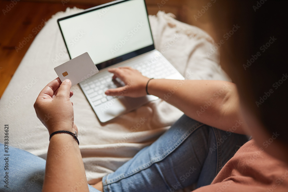 Obraz premium Close-up of woman paying online by credit card using her laptop on the bed in the bedroom