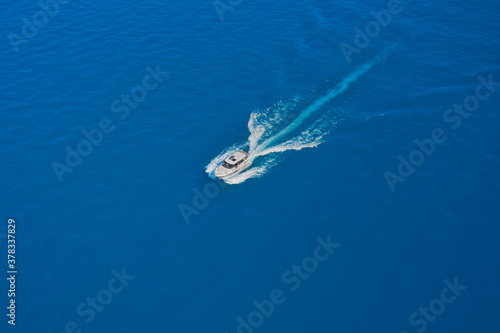 Aerial view luxury motor boat. High-speed yacht of white color fast motion on blue water in the rays of the sun top view. Travel - image. Speed boat movement at high speed aerial view.