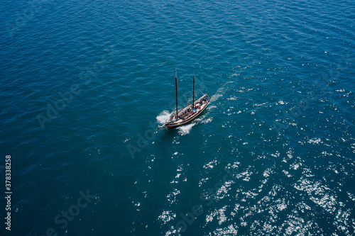 Aerial view to yacht with people in deep blue sea. Drone photography