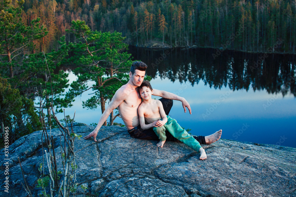 middle age man with little cute son doing sport yoga on the top of the mountain together, happy family lifestyle people outdoor, summer wild nature for training middle age man with little cute son doing sport yoga on the top of the mountain together, happy family lifestyle people outdoor, summer wild nature for training