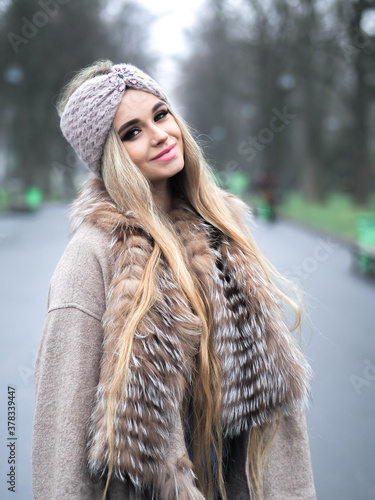 Obraz na płótnie Blonde girl posing at the winter city in a fur coat and a hat w salonie