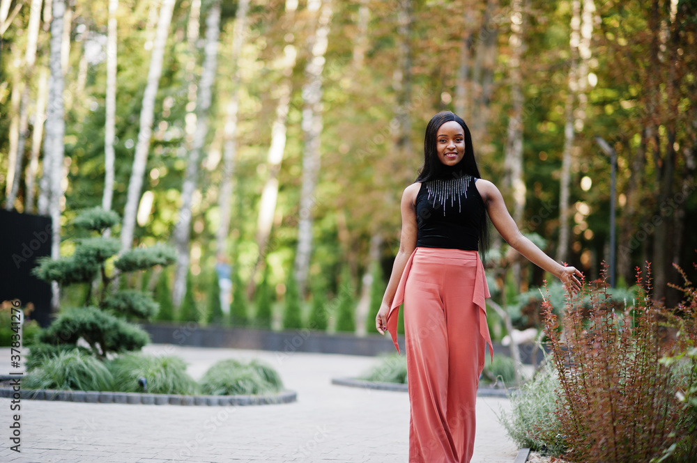 Fashionable african american woman in peach pants and black blouse pose outdoor. Fashionable african american woman in peach pants and black blouse pose outdoor.