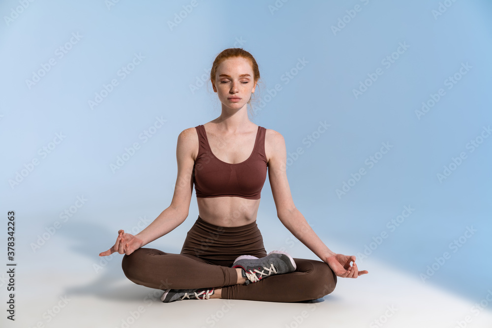 Fototapeta premium Photo of concentrated sportswoman meditating while working out