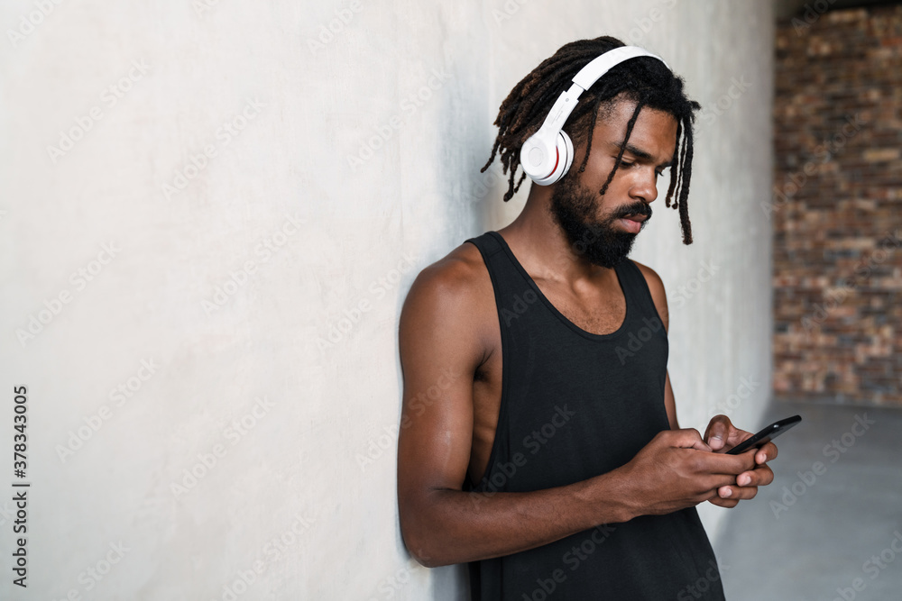 Fototapeta premium Image of african american sportsman using cellphone and headphones