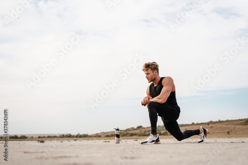Photo of athletic young sportsman doing exercise while working out