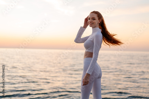 Image of pleased redhead sportswoman smiling at camera while working out