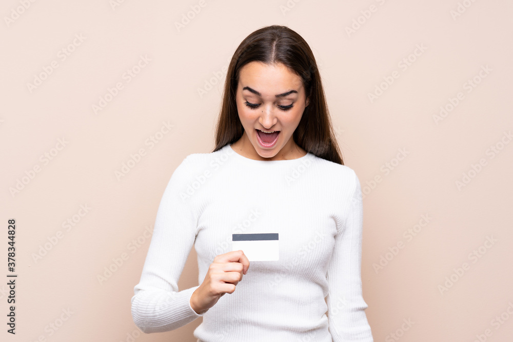 Young woman over isolated background holding a credit card Young woman over isolated background holding a credit card