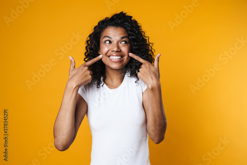 Image of african american girl pointing fingers at her cheeks