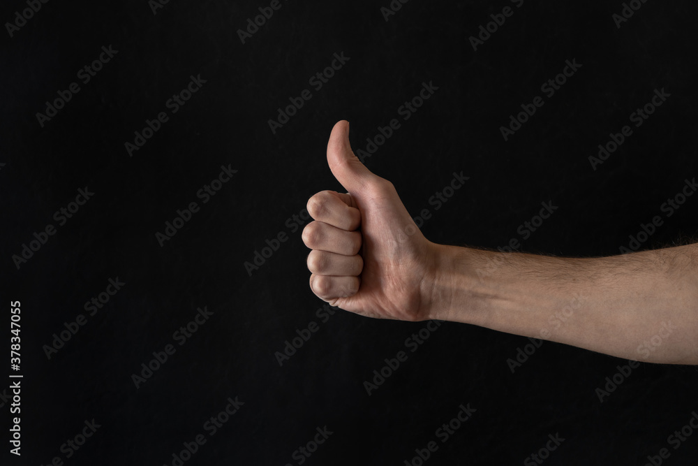 Man's hand thumbs up, approval concept. Isolated on black background. Man's hand thumbs up, approval concept. Isolated on black background.