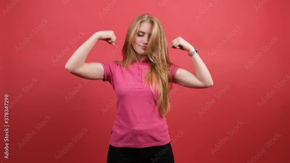 Young woman points to the strong hands on a red background. Young woman points to the strong hands on a red background.