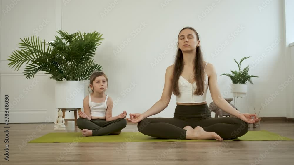 Mom and daughter practice yoga. Meditate in the lotus position. Health Mom and daughter practice yoga. Meditate in the lotus position. Health