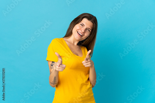 Young slovak woman isolated on blue background pointing to the front and smiling