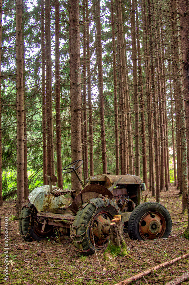 abandoned old rusty tractor left in a pine forest