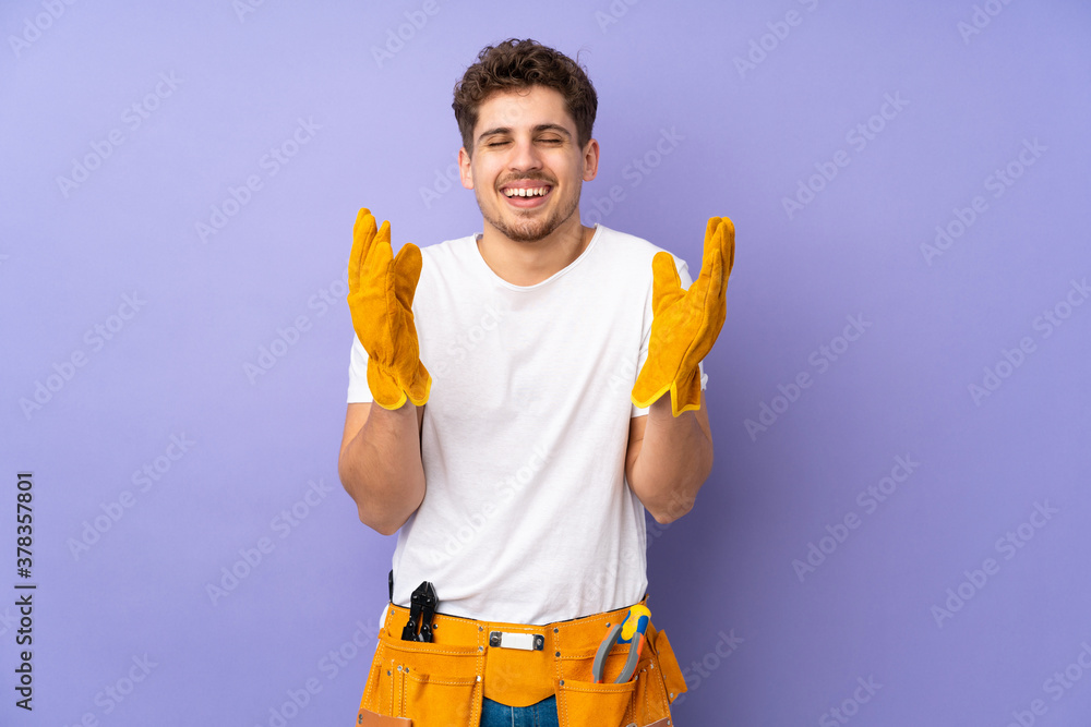 Young electrician man over isolated on purple background laughing Young electrician man over isolated on purple background laughing