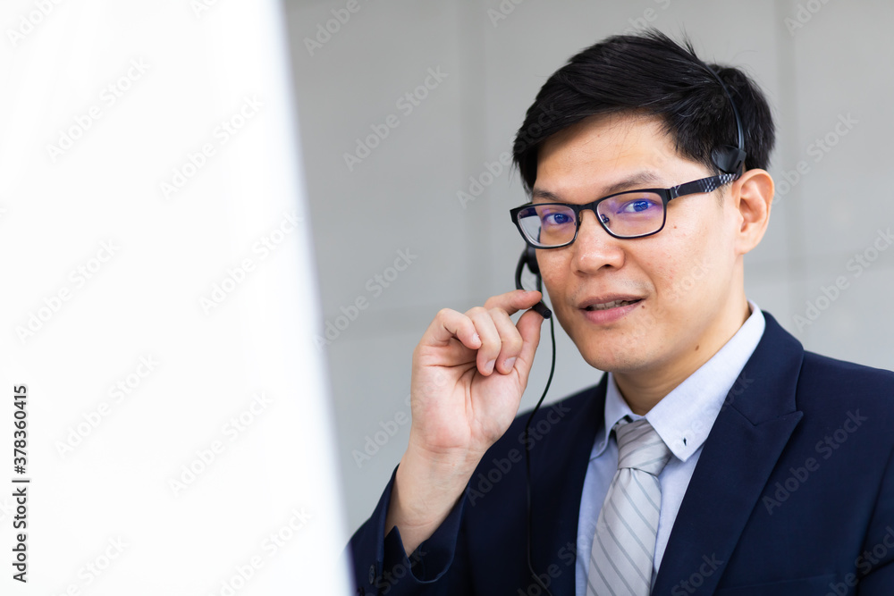 Attractive Asian Businessman work with phone, headset at call center and telemaketing sale support workplace. Customer service assistant working in office. Communication, sale support, Attractive Asian Businessman work with phone, headset at call center and telemaketing sale support workplace. Customer service assistant working in office. Communication, sale support,