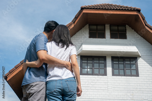 Happy couple in front of the New Home On Moving In Day, and start a new life family. Concept of homeowner and relocation © Prot
