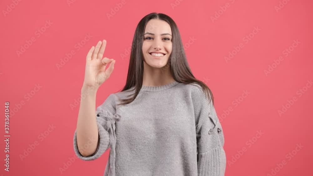 Happy young woman showing ok sign with fingers isolated on a red background. Happy young woman showing ok sign with fingers isolated on a red background.