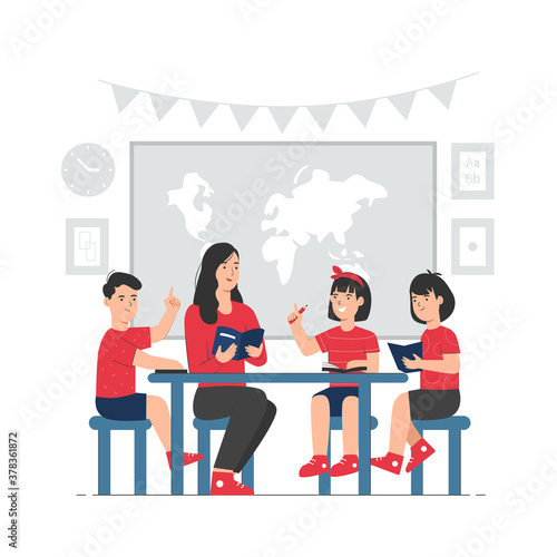 Teacher with students sitting at table and reading book together in classroom