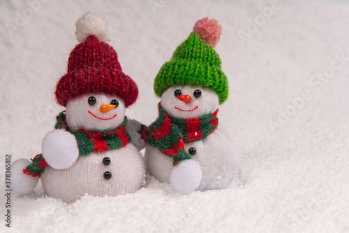 Two cute snowmen stand in the snow and smile during snowfall with copy space. Concept christmas.