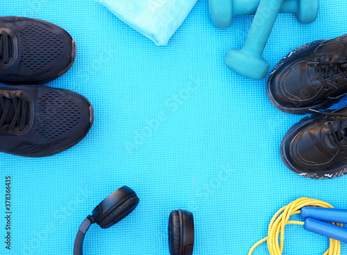 sport fitness concept, space for text, black sneakers, blue dumbbells, headphones, fitness jump rope template