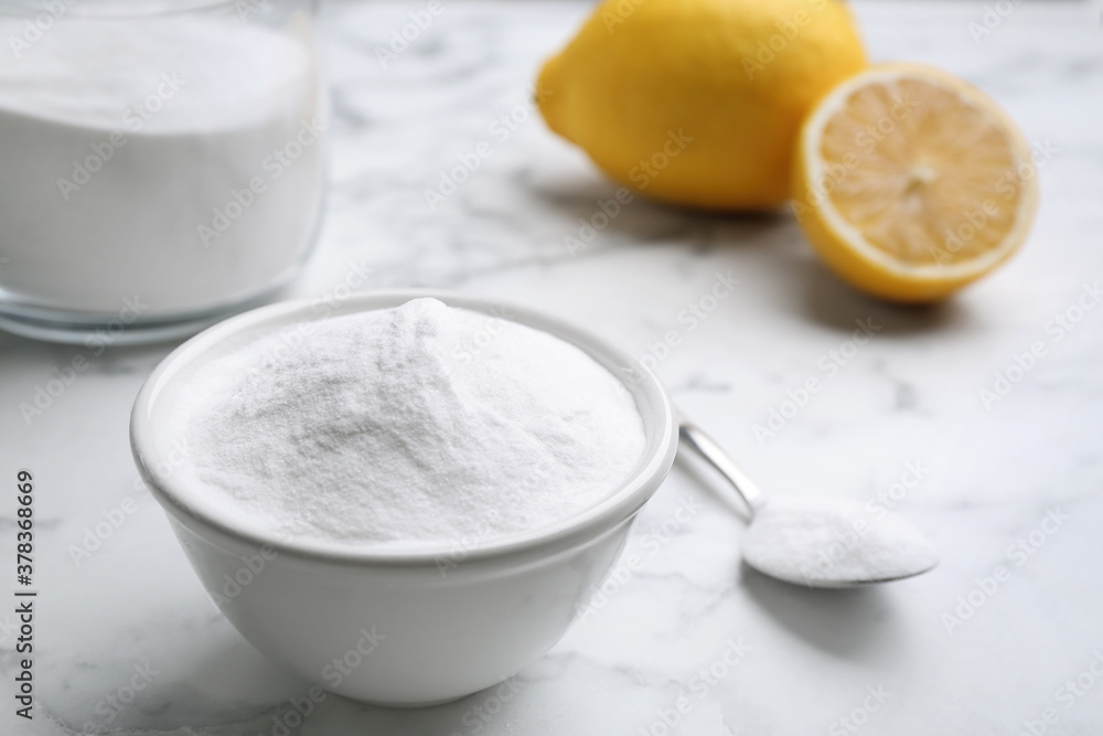 Baking soda and cut lemons on white marble table Baking soda and cut lemons on white marble table