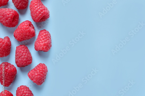 Fresh sweet ripe raspberries on light blue background  flat lay. Space for text