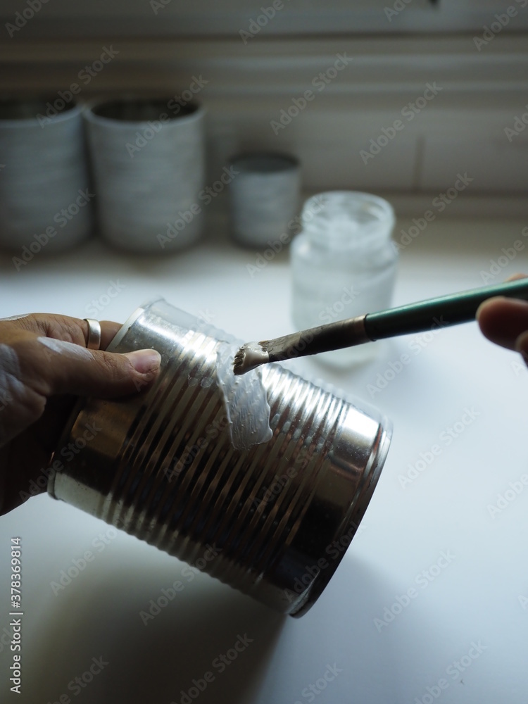 hand of a young woman painting a metal can