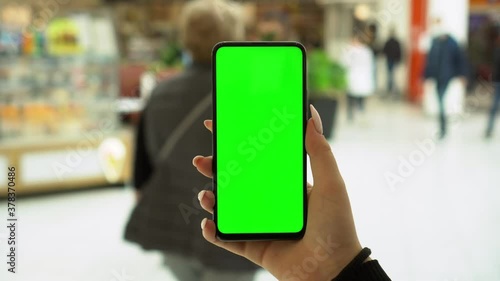 Wallpaper Mural Shopping center. Back view of brunette holding chroma key green screen smartphone watching content. Gadgets and contemporary people concept. Torontodigital.ca